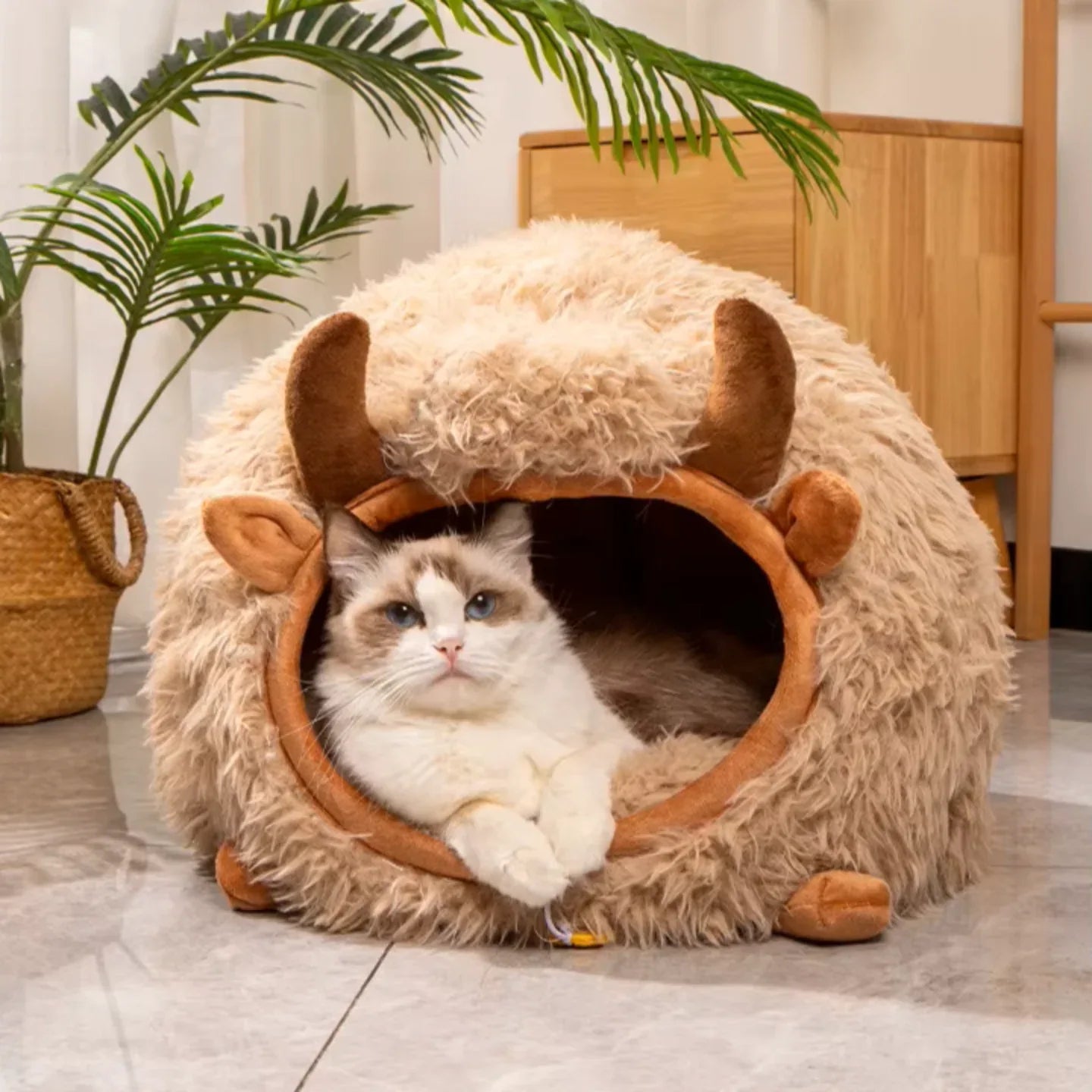 Gato deitado confortavelmente dentro da cama par gato em formato de touro  